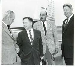 ["Black and white photograph print of Carl Albert standing with three unidentified men at an airport during the trip to Bogota, Columbia."]