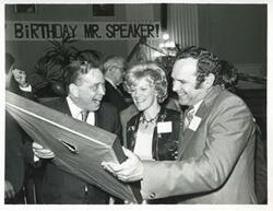 ["Black and white photograph print of Carl Albert holding up his new portrait of Oklahoma football on his birthday. 1976"]