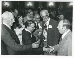 ["Black and white photograph print of Carl Albert shaking hands with an unidentified man. John W. McCormack is also pictured."]