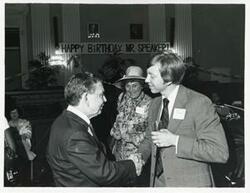 ["Black and white photograph print of Carl Albert shaking hands with Bill Stephens. Bella Abzug is in the background at Albert's birthday party, 1976"]