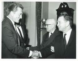 ["Black and white photograph print of Carl Albert shaking hands with Kirk Douglas."]