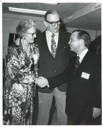 ["Black and white photograph print of Carl Albert shaking hands with an unidentified woman."]