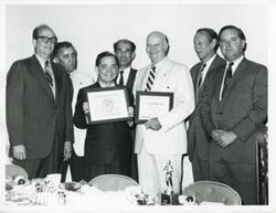 ["Black and white photograph print of Carl Albert and Robert L. F. Sikes. They are holding two plaques."]