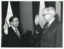 ["Black and white photograph print of Carl Albert standing with Congressman George V. Hansen from Idaho. They are reenacting swearing-in. May 1971"]