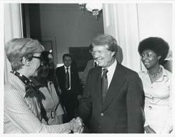 ["Black and white photograph print of Jimmy Carter shaking hands with an unidentified woman as Shirley Jeter looks on. June 24, 1976"]