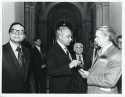 ["Black and white photograph print of Robert Strauss, Robert C. Byrd, and another man speaking to one another at a Democratic leadership conference."]