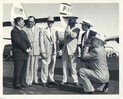 ["Black and white photograph print of Carl Albert with a group of men at an airport."]