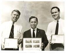 ["Black and white photograph print of Carl Albert with Wes Watkins and an unidentified man (all) holding pictures and plaques concerning the Kiamichi Area vocational technical schools"]