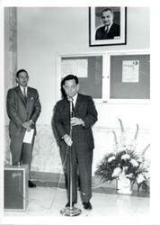 ["Carl Albert adjusting a microphone."]