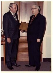 ["Color photograph of Tom Steed with Rex Davis, director of the Bureau of Alcohol, Tobacco and Firearms standing with an award."]